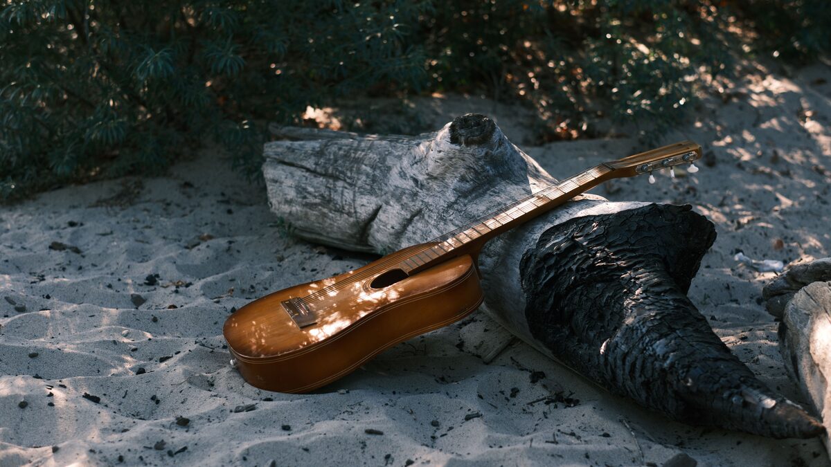 A nylon-string guitar resting on a chair by a sunlit window