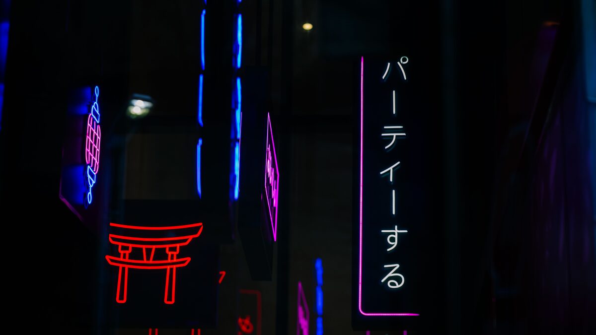 Neon-lit Tokyo street at night reflected in a rain-slicked road