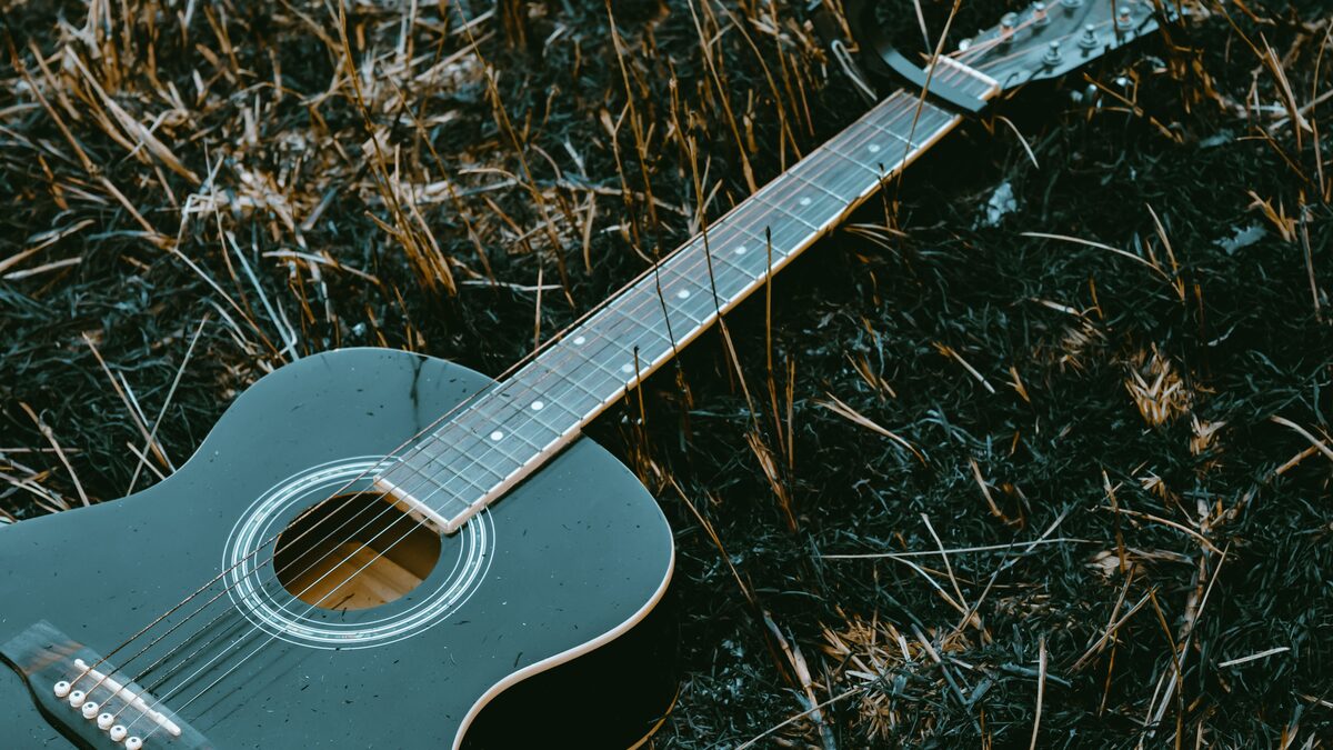 Acoustic guitar and cowboy hat on a wooden porch at sunset