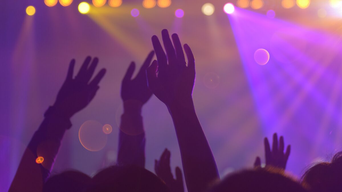 A dark club with a single bright strobe over a crowd