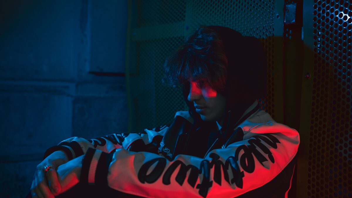 Dimly lit bedroom with an electric guitar leaning against the wall