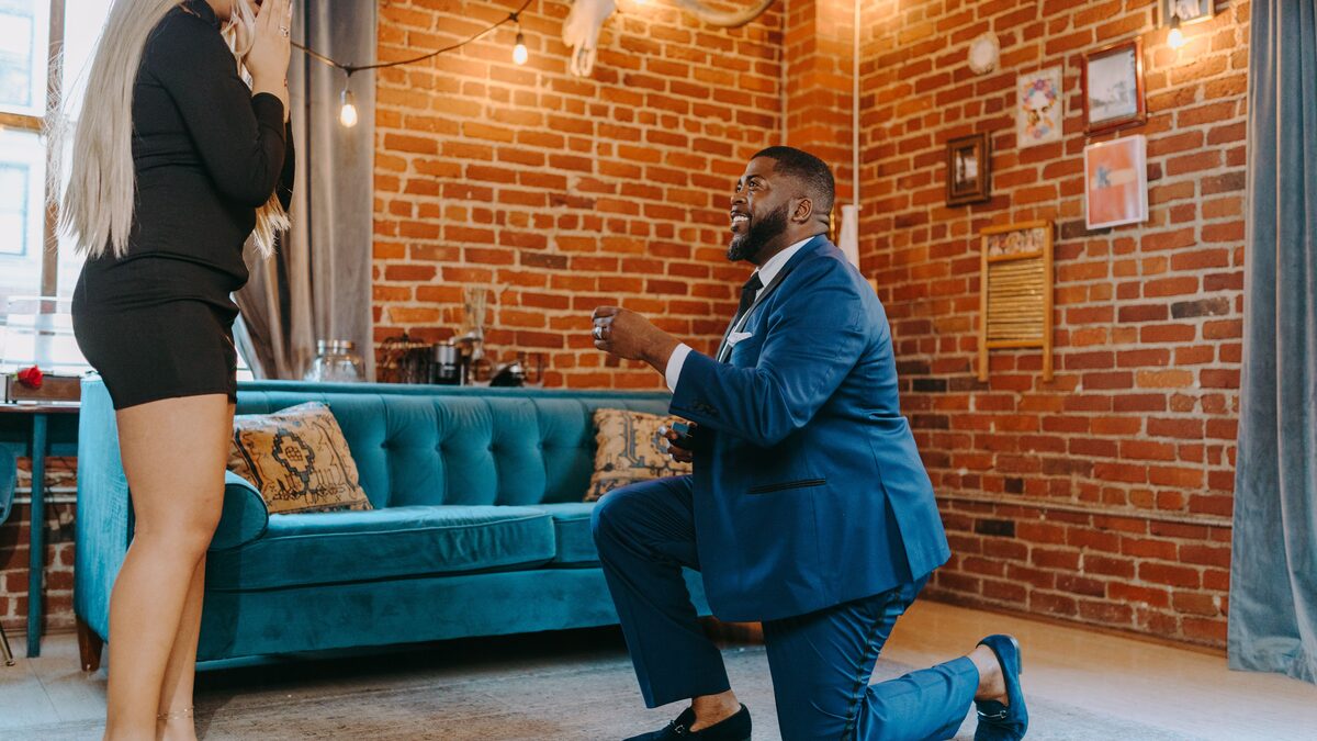 A person proposing with a ring in a warm, romantic indoor moment