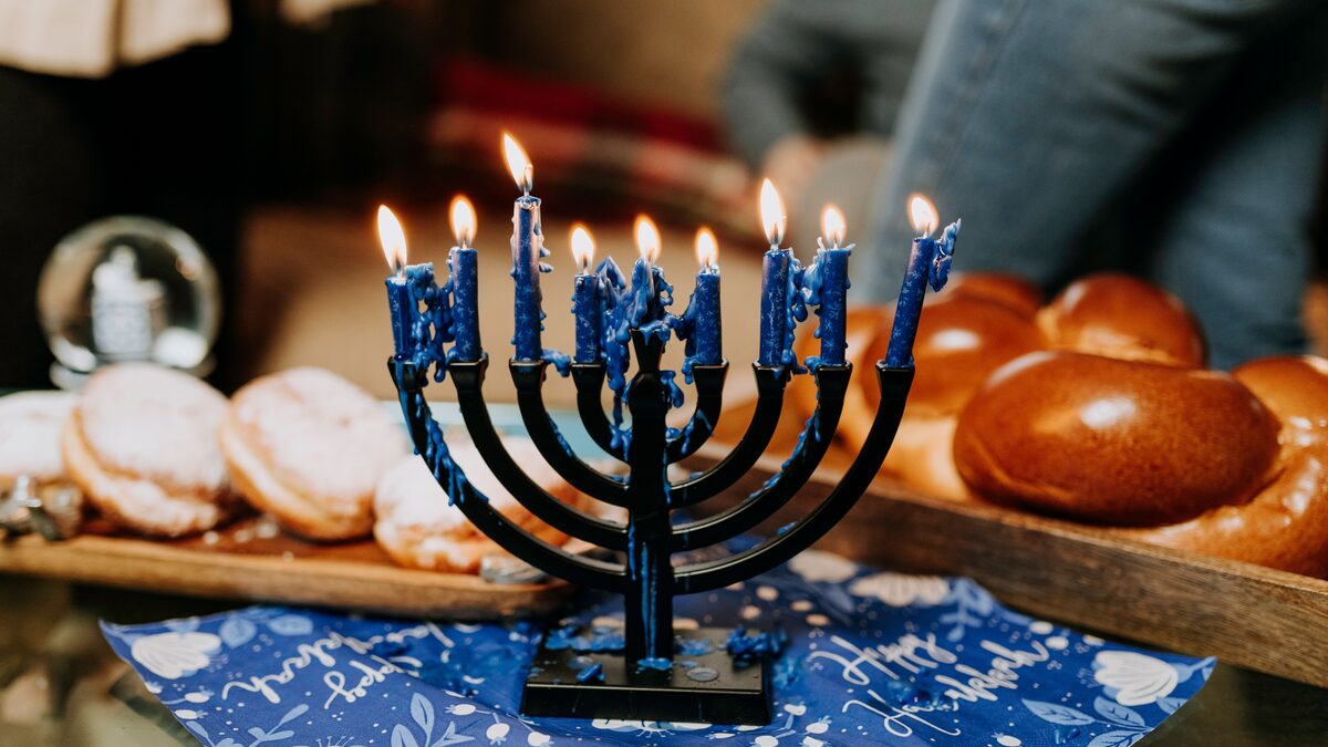 A lit menorah glowing warmly on a windowsill during Hanukkah