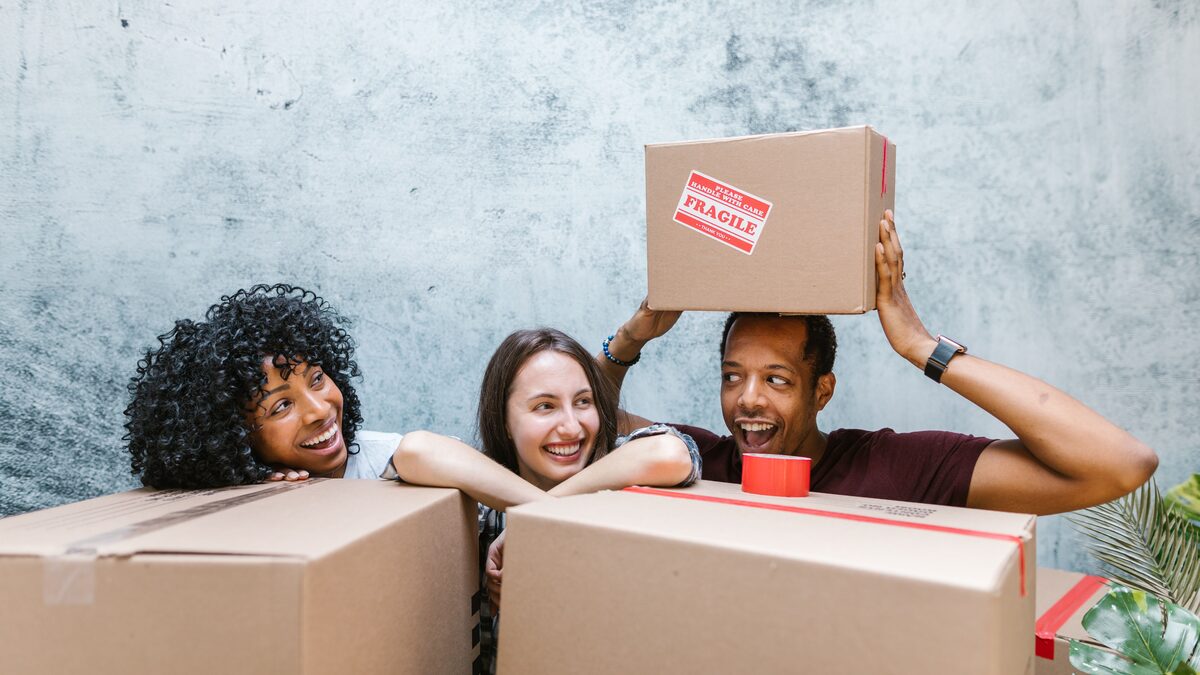 friends smiling together in a new home among moving boxes