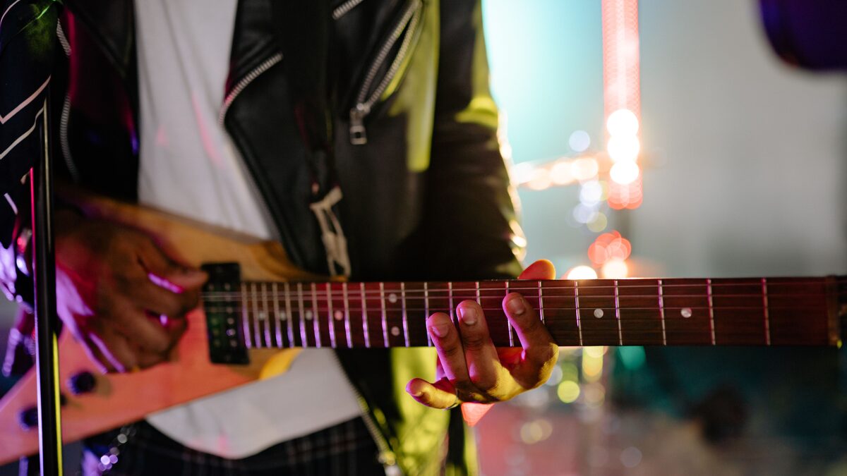 A guitarist's hands tapping across the fretboard of an electric guitar