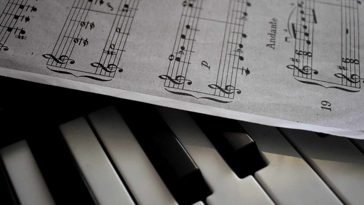 A person humming a tune while sketching notes at a desk