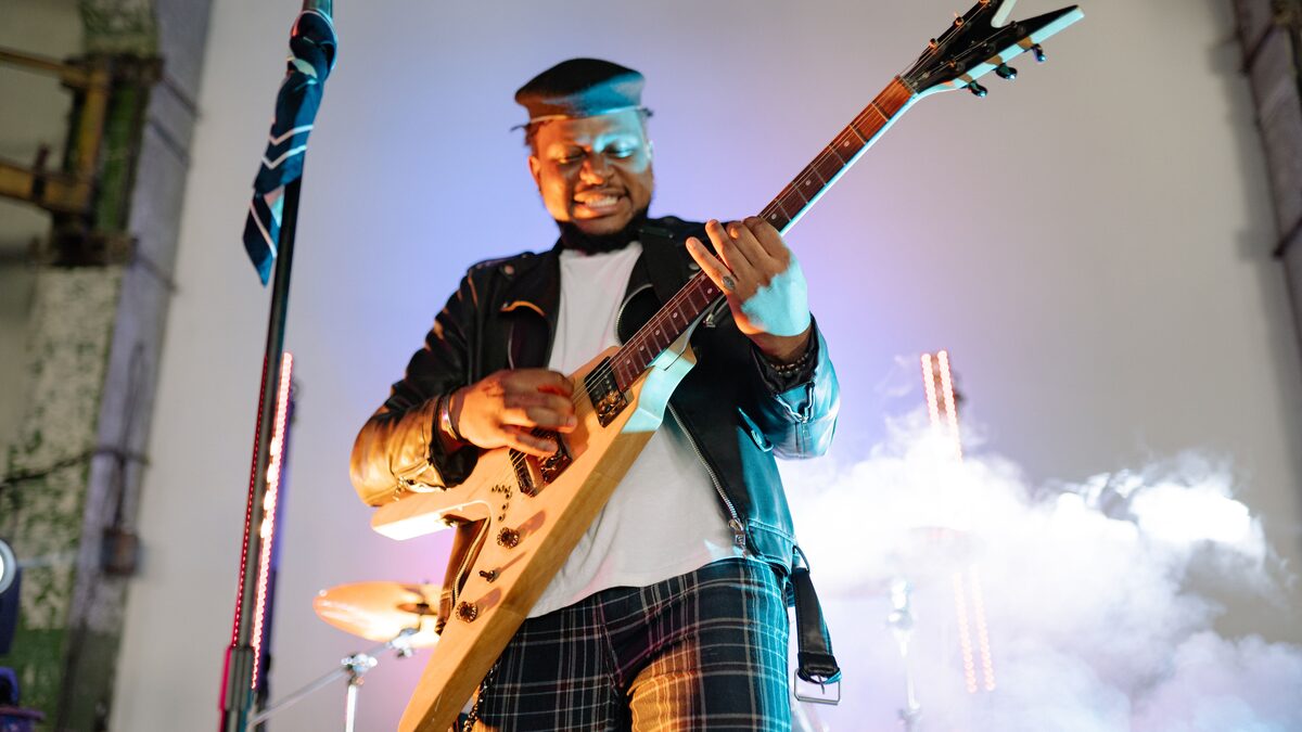 Metal guitarist playing a low slung electric guitar under red stage lighting