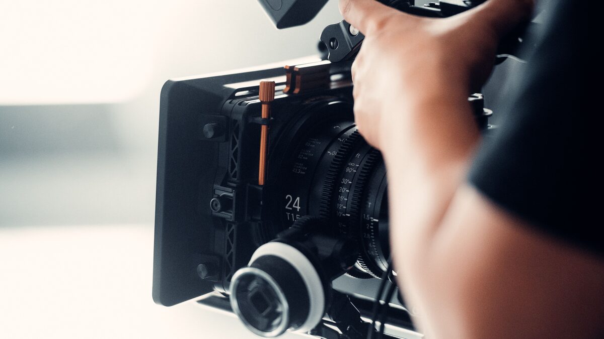 A video editing timeline on a monitor with an audio track and a small studio speaker nearby