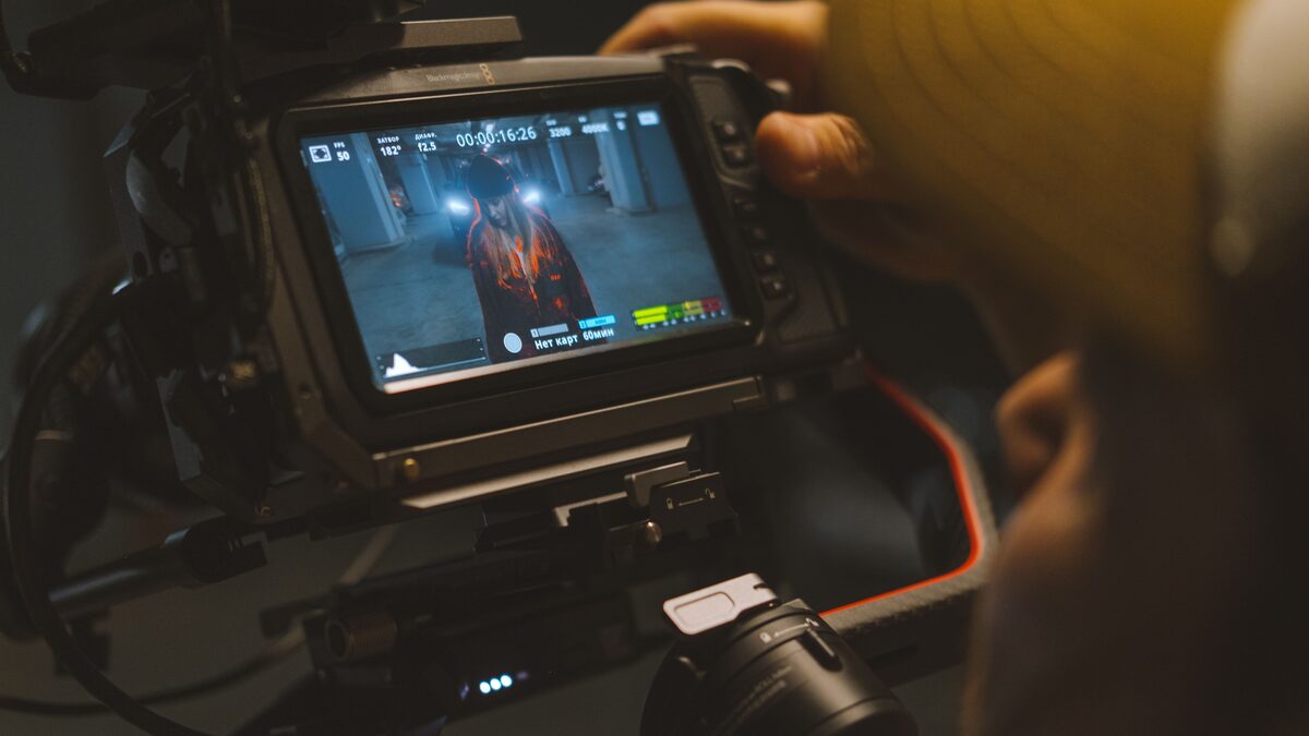 ALT: Editor scoring a short film on a laptop with headphones in a dim room