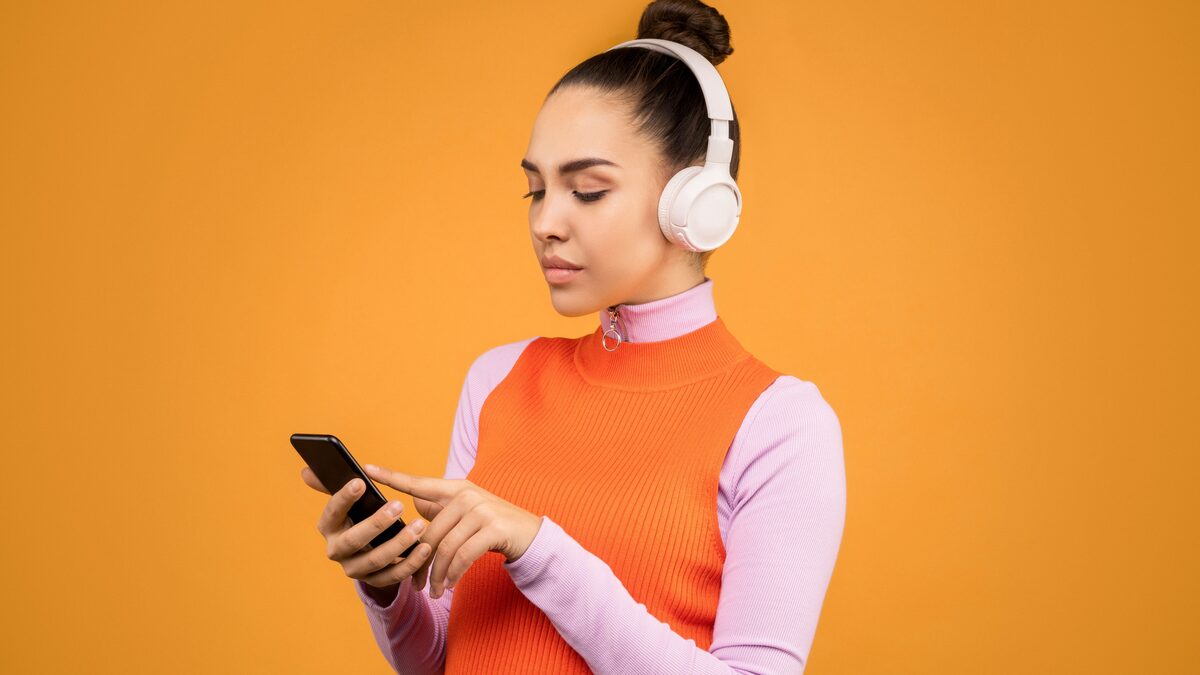 Phone showing a music streaming app next to headphones on a desk