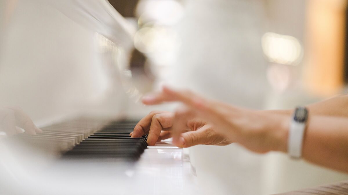 A grand piano beside a laptop and audio interface in a home studio
