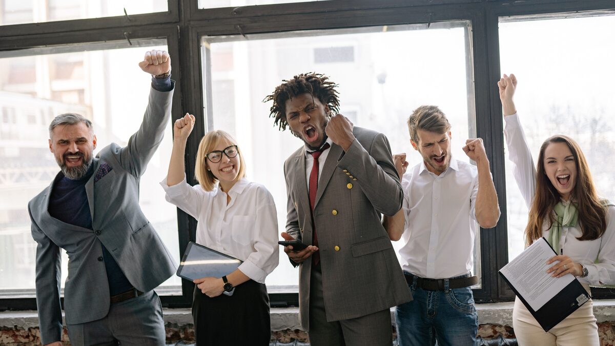 Coworkers raising coffee mugs in a bright office to celebrate a colleague
