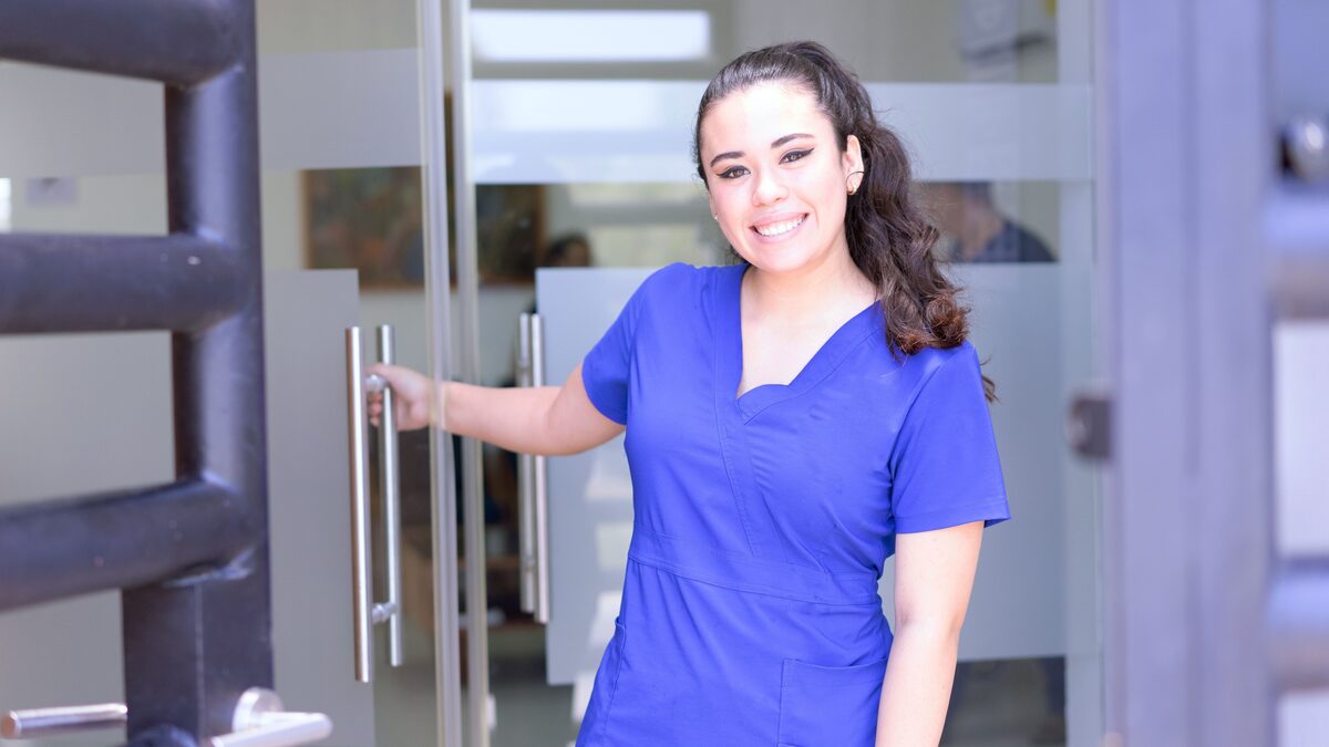 A nurse in scrubs holding a patient's hand in a quiet hospital room