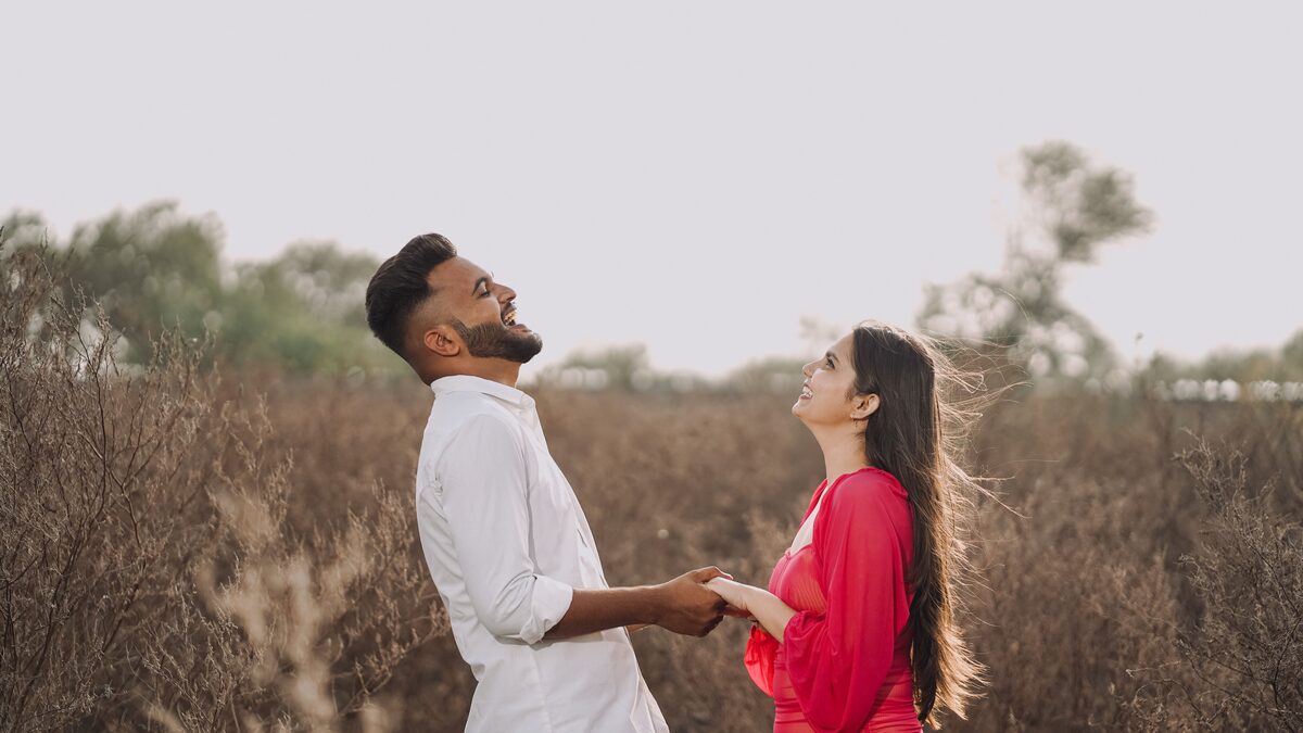 A couple sharing headphones and smiling while listening to music together