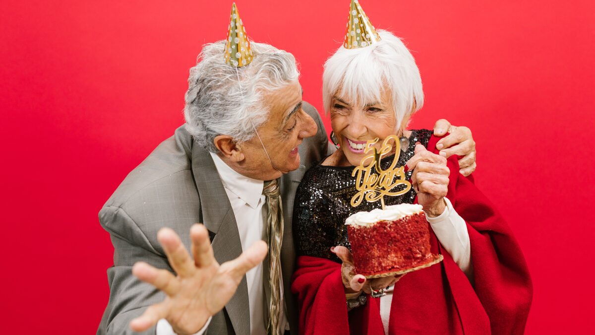 An older couple's hands resting together over an open family photo album