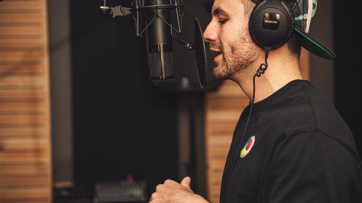 A person recording rap vocals into a microphone at a home studio desk