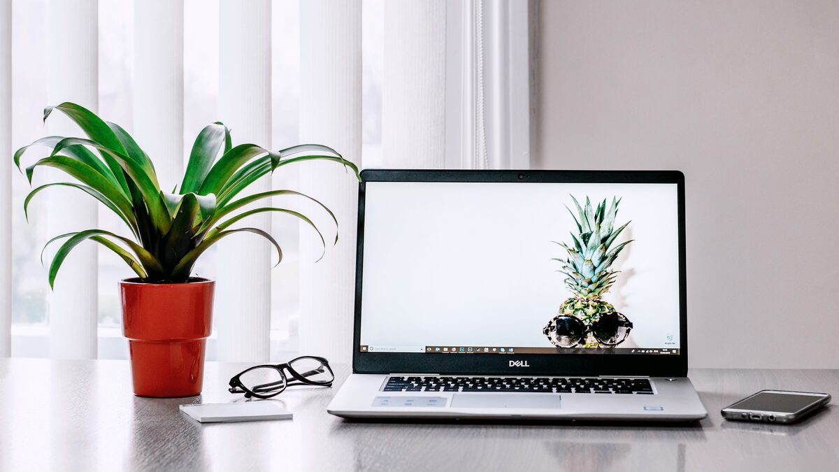 A laptop on a desk with headphones and an audio waveform on screen
