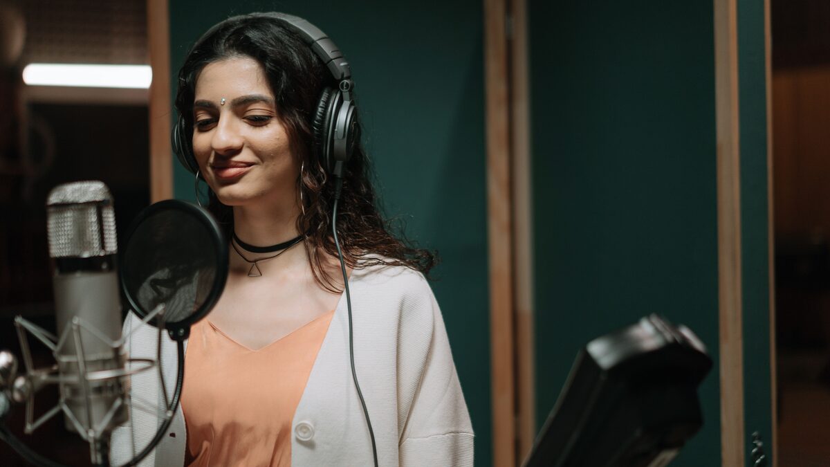 Singer recording vocals into a microphone in a home studio setup