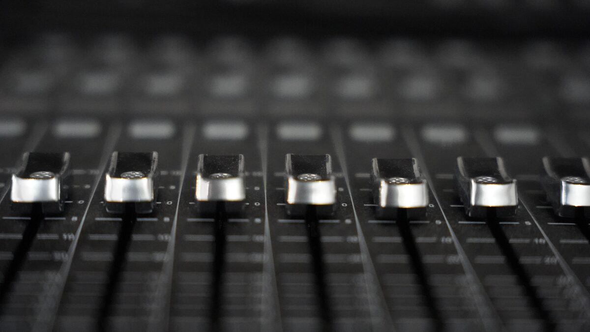 a close-up of audio mixer faders in a studio