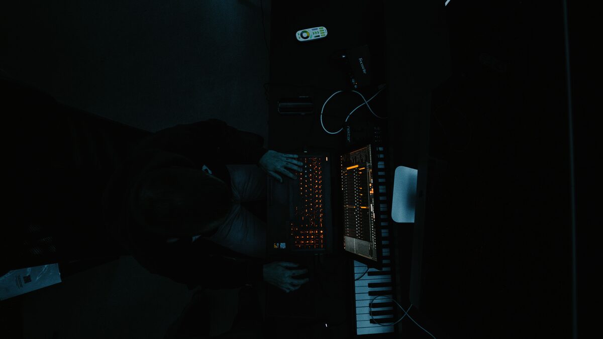 a music producer at a laptop in a dim studio