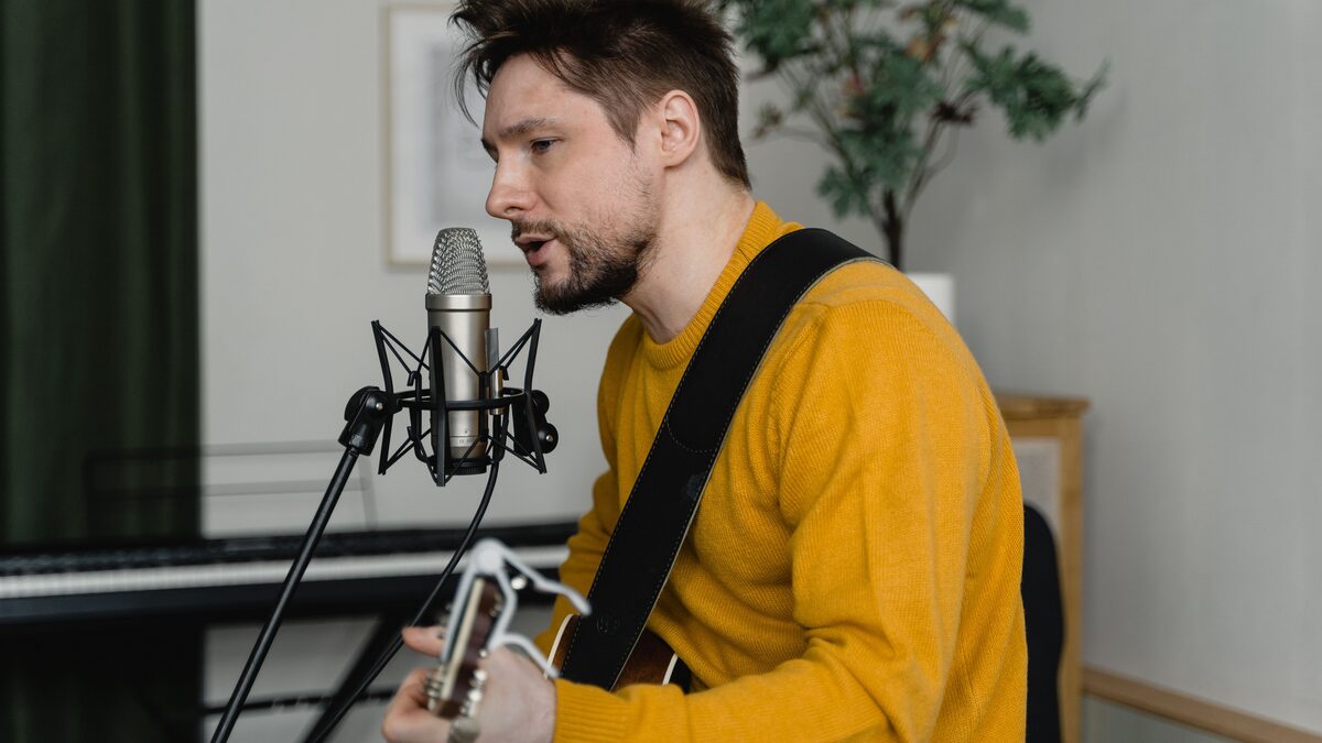 A songwriter humming a melody while writing lyrics in a notebook